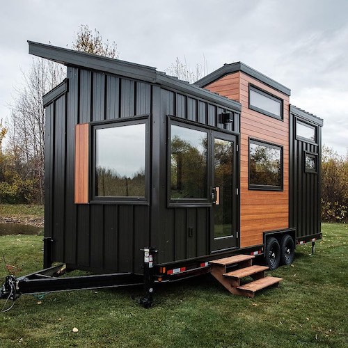 black and wood Fritz tiny house on wheels in green yard
