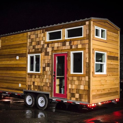 wood Rewild tiny house on wheels in parking lot at night