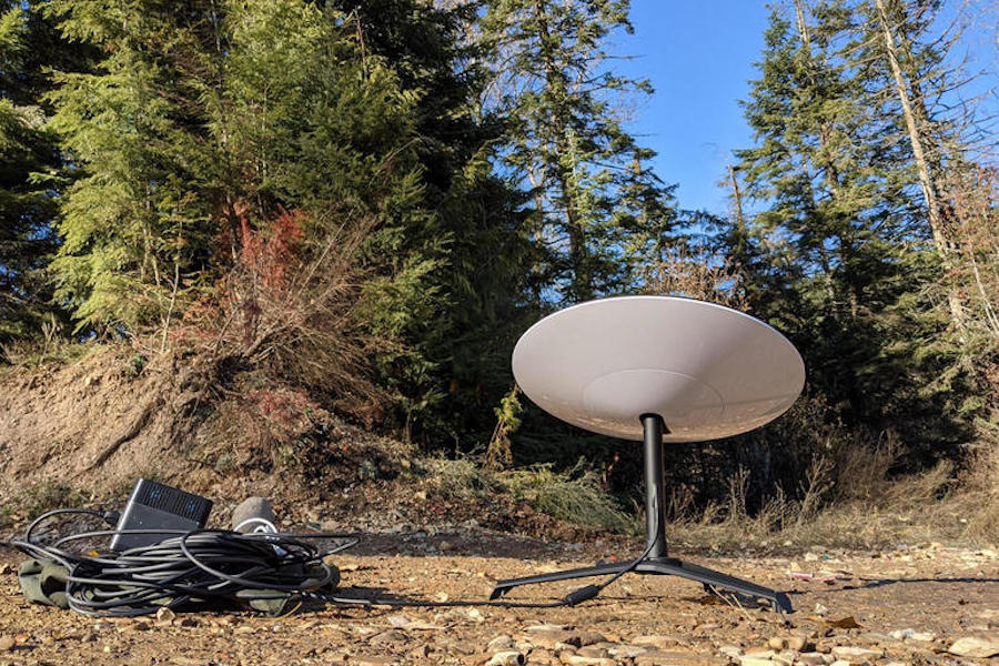 Starlink satellite dish and cables on ground in forest