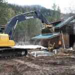 excavator and crew placing septic tanks next to a barn-loft