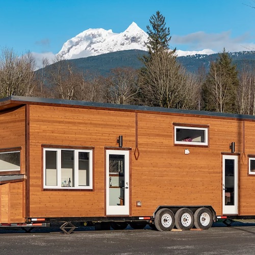 Long tiny home on wheels with mountain background
