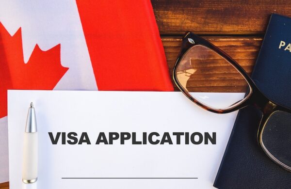 table with Canada flag, passport, and visa application