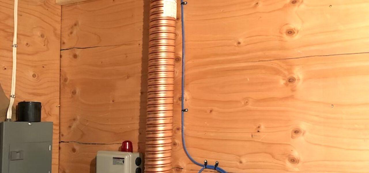Wide copper coil drain pipe affixed to a wall